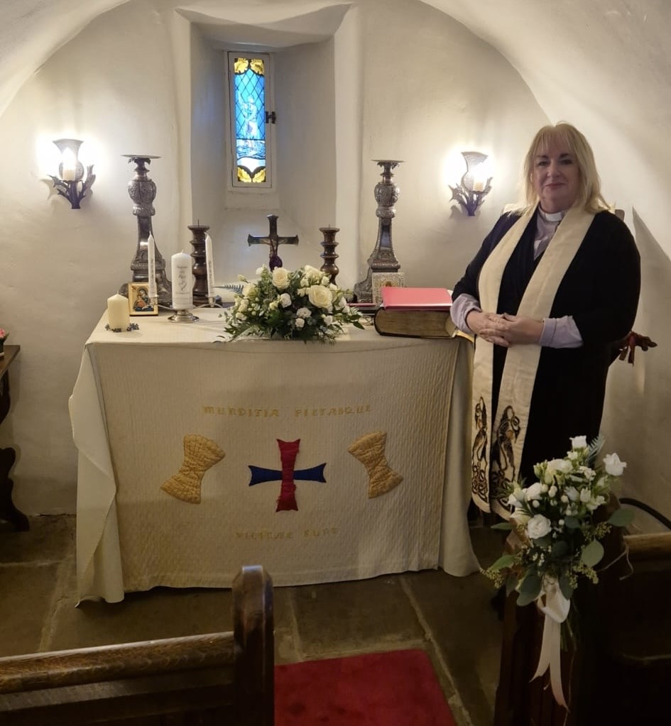 Rev. Marie-Louise Jones standing at a wedding altar in a historic chapel